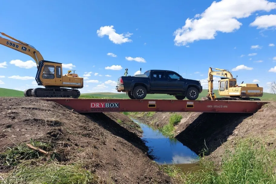 A truck crossing a bridge made from 40ft flat rack containers