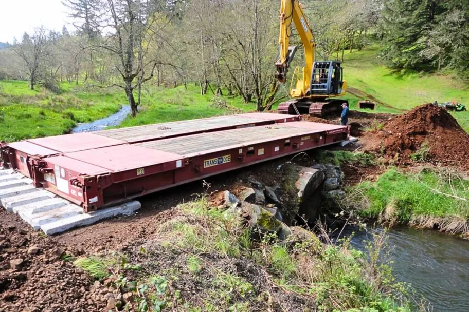 40ft flat rack used as a bridge over a creek with an excavator