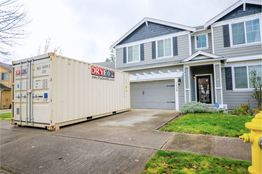 A clean white shipping container delivered in a residential driveway