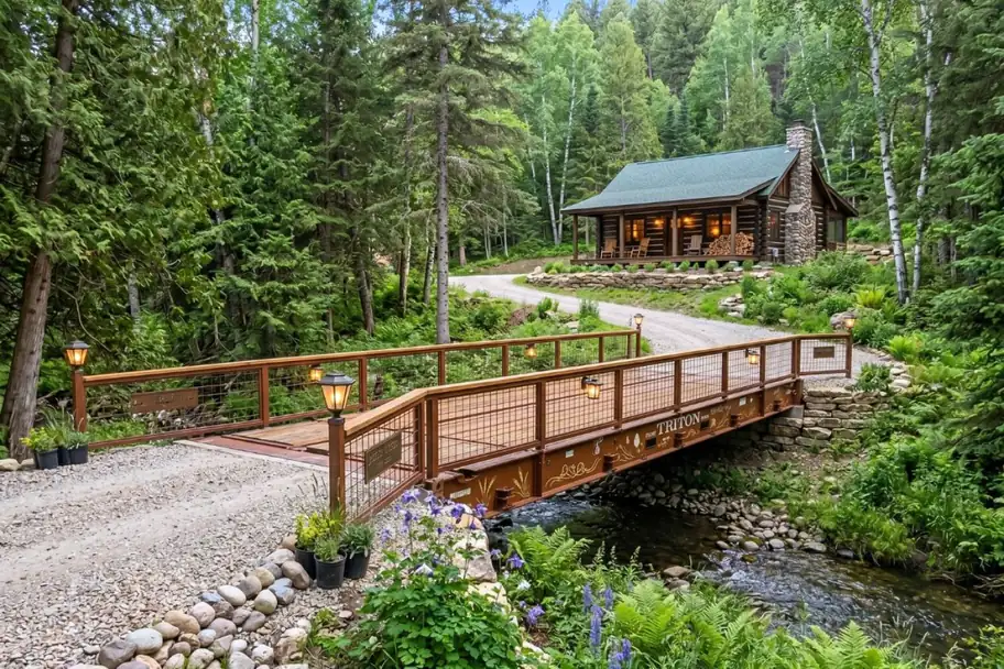 A flat rack container bridge over a creek leading to a forest cabin