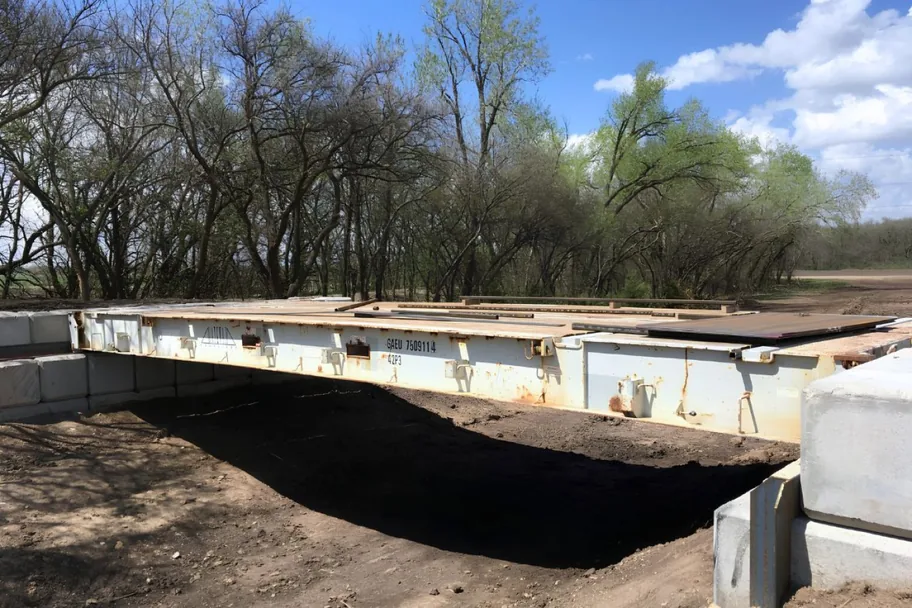 A single flat rack container bridge spanning a dry creek bed
