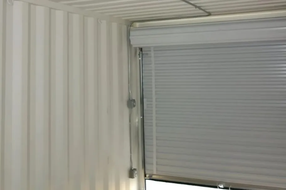 Interior of a shipping container looking out through an open rollup door