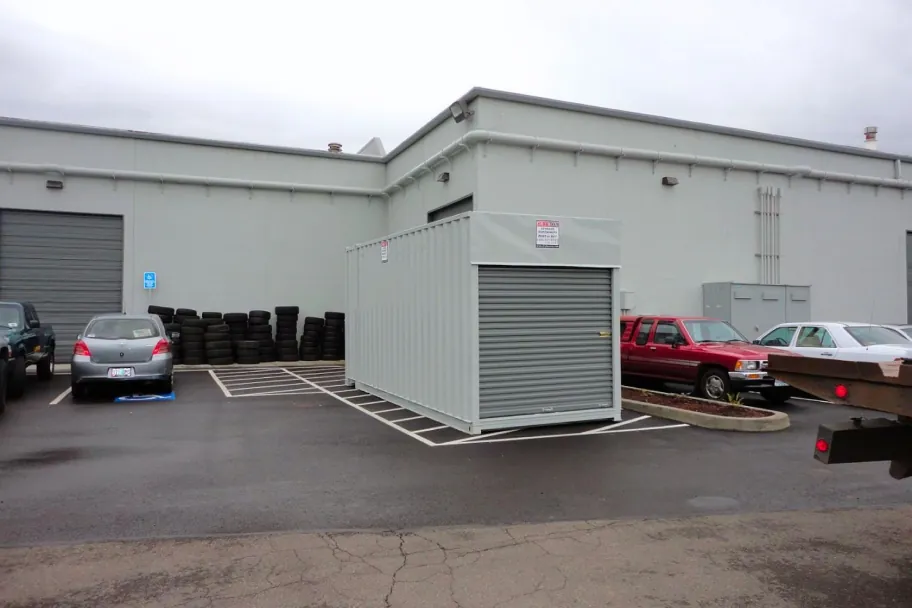 A grey shipping container color matched to an adjacent commercial building