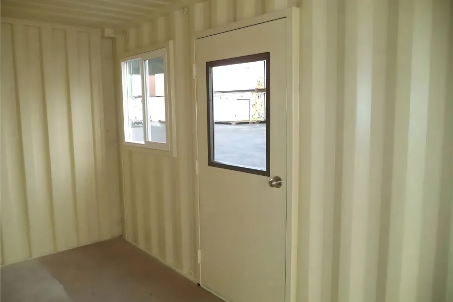 A container interior finished in light primer with a personnel door and window