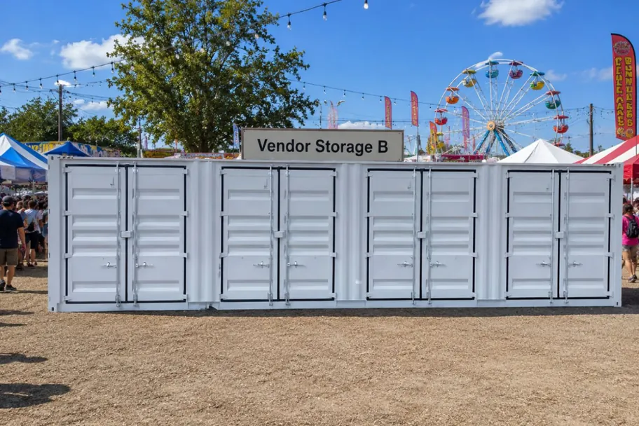 A white multi-door side-access shipping container labeled Vendor Storage B at a fair
