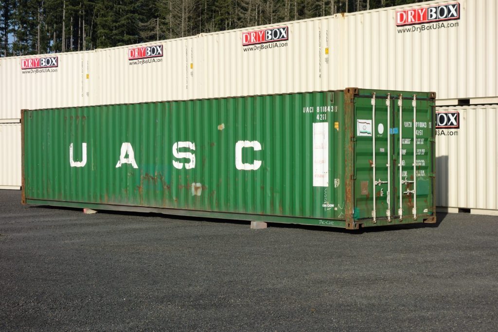 green shipping container next to gray containers