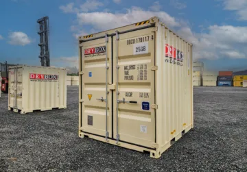 A six-foot wide, beige shipping container rental, on gravel.