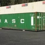 green shipping container next to gray containers