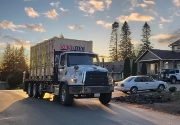 Three six-foot wide shipping containers are being delivered to a house