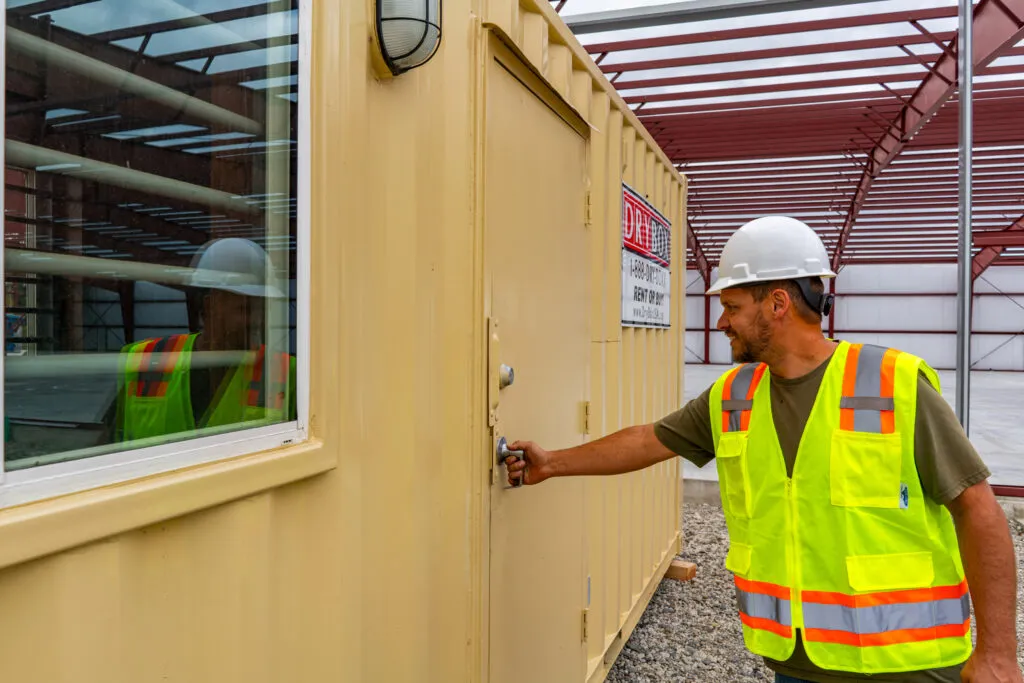 A construction worker opens the door to a 20ft Dry Box Ground Level Office.