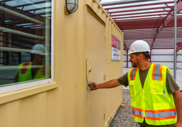 A construction worker opens the door to a 20ft Dry Box Ground Level Office.